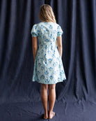 Woman wearing a floral dress against a dark curtain