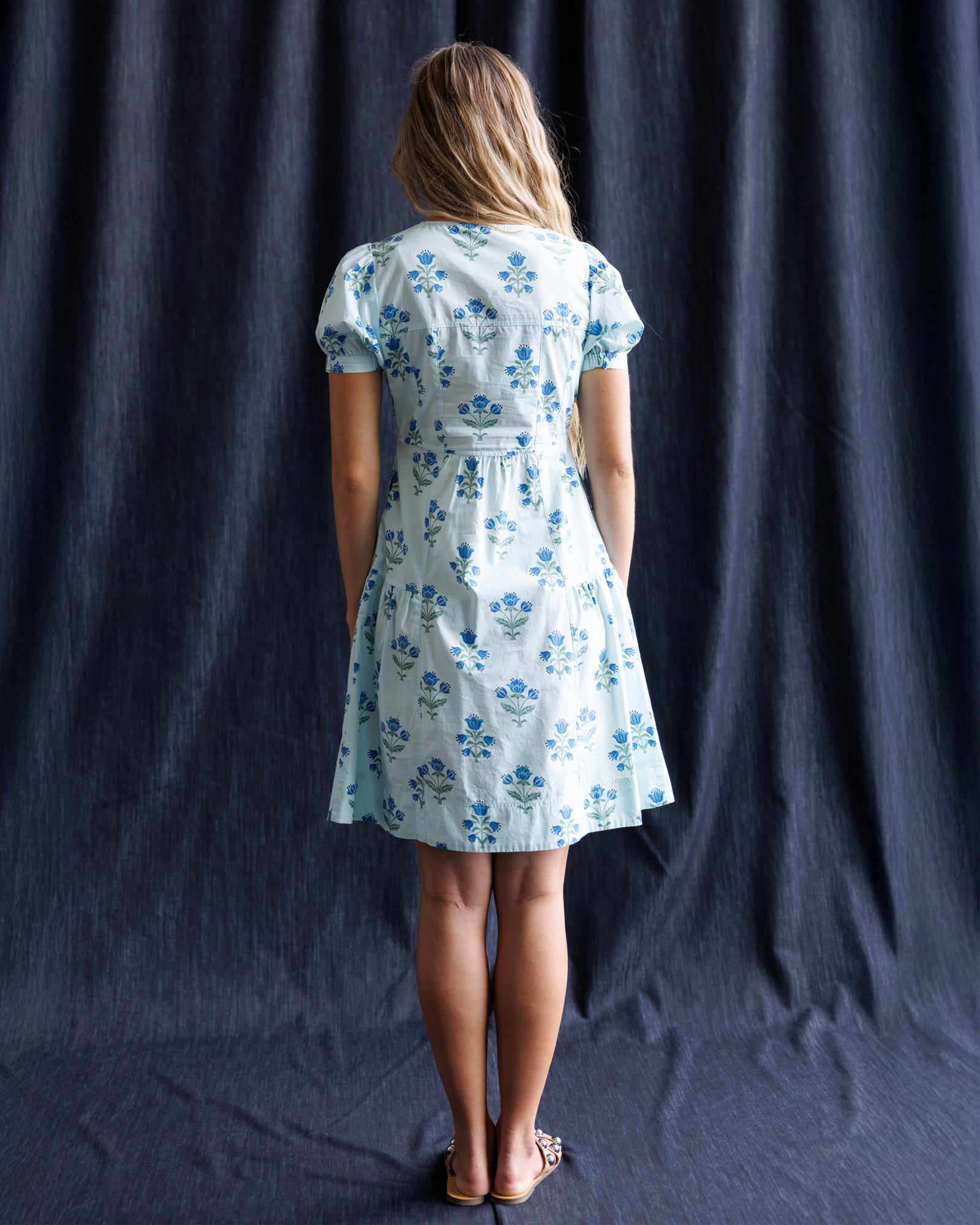 Woman wearing a floral dress against a dark curtain