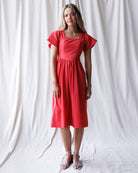 Woman wearing a red dress against a white curtain background