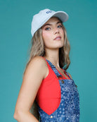 Woman wearing a blue patterned dress over a red tank top against a teal background