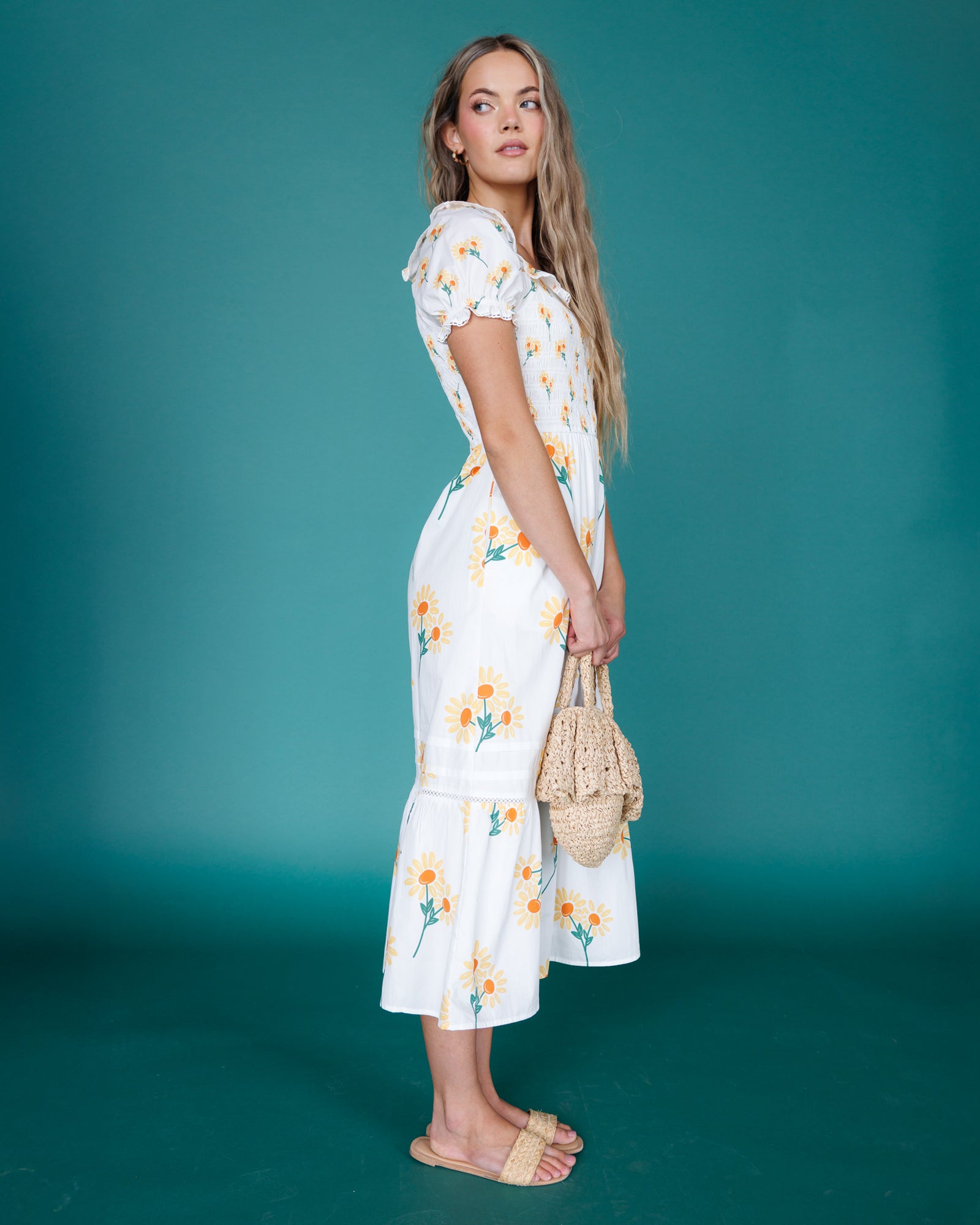 Woman wearing a white floral dress against a teal background