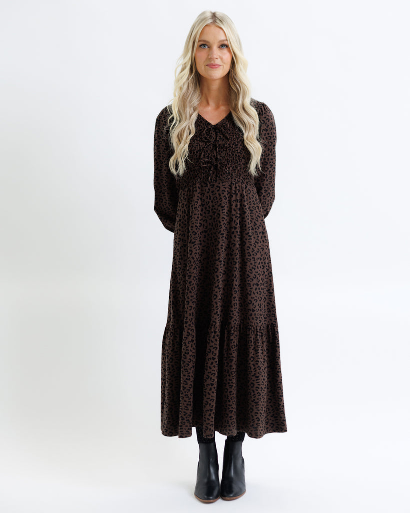 Woman wearing a long brown dress with a pattern on a white background