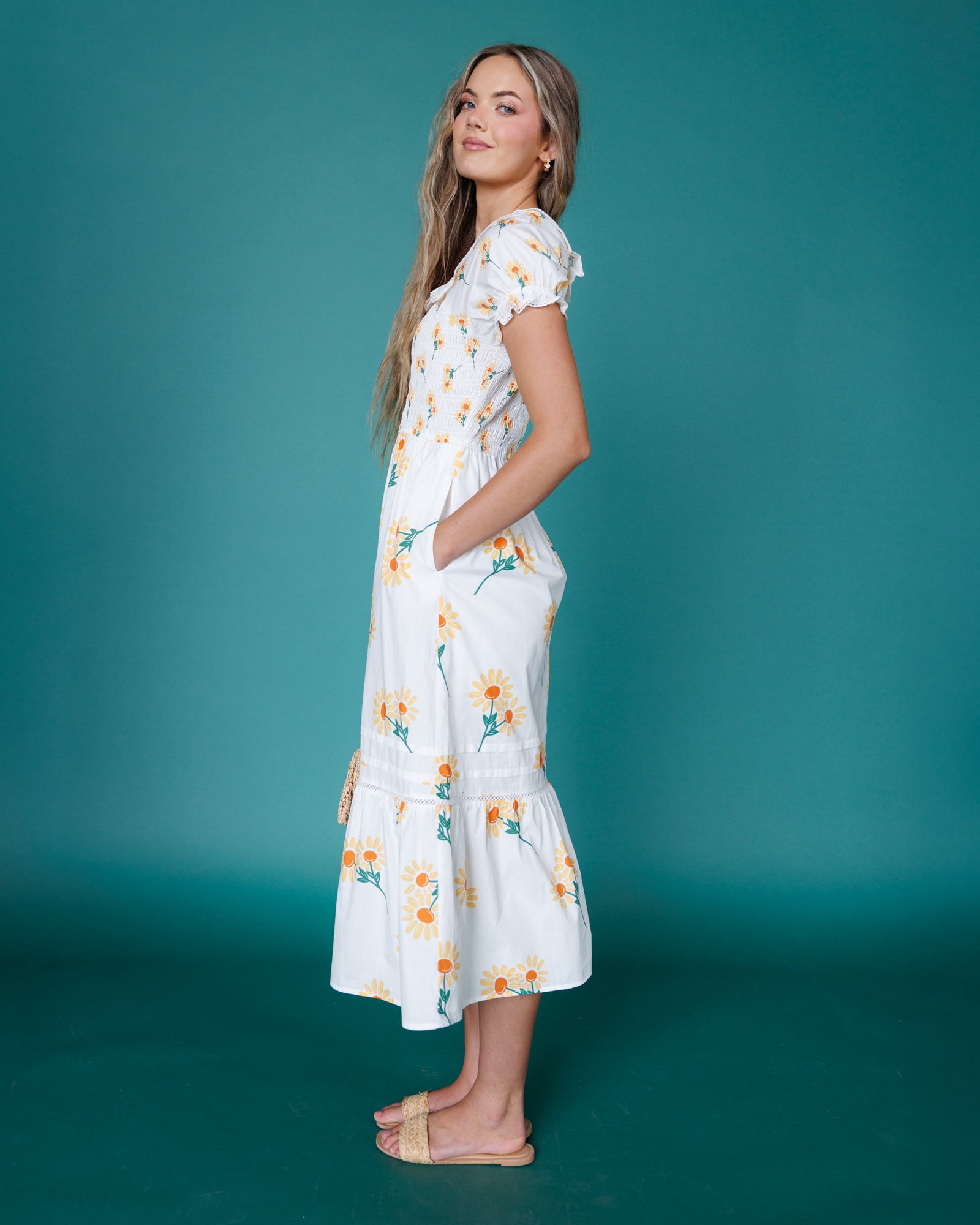 Woman wearing a white floral dress against a teal background