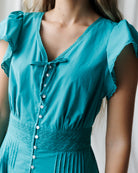 Teal dress with button details on a neutral background