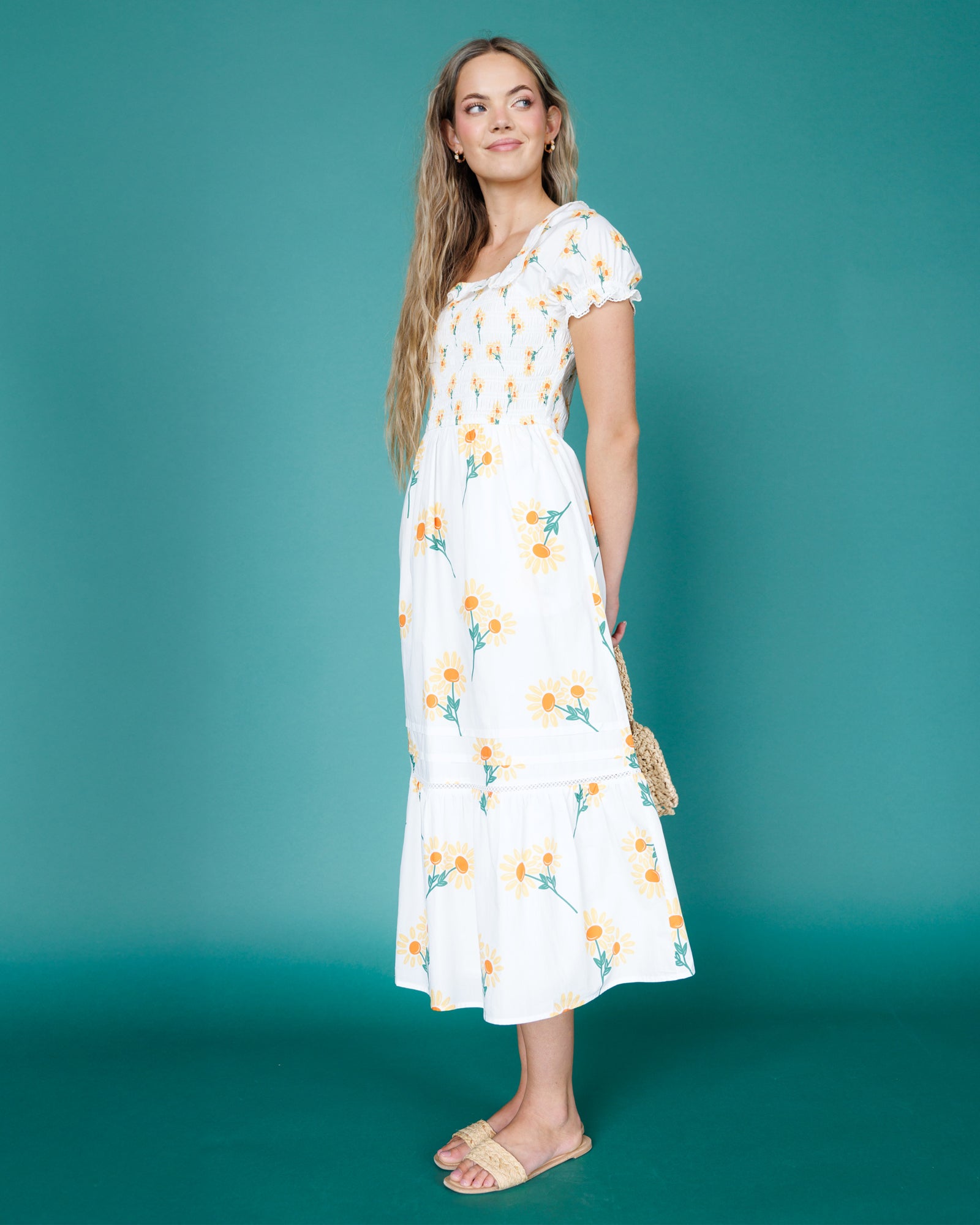 Woman wearing a white floral dress against a teal background