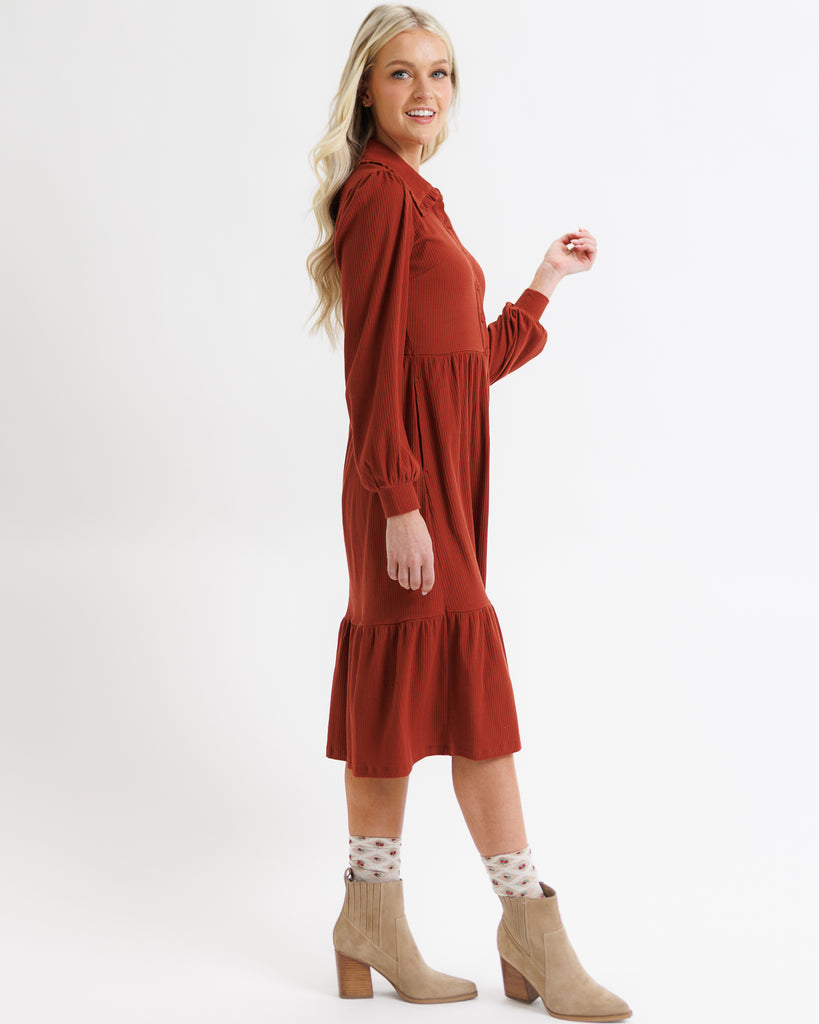 Woman wearing a rust-colored dress on a white background