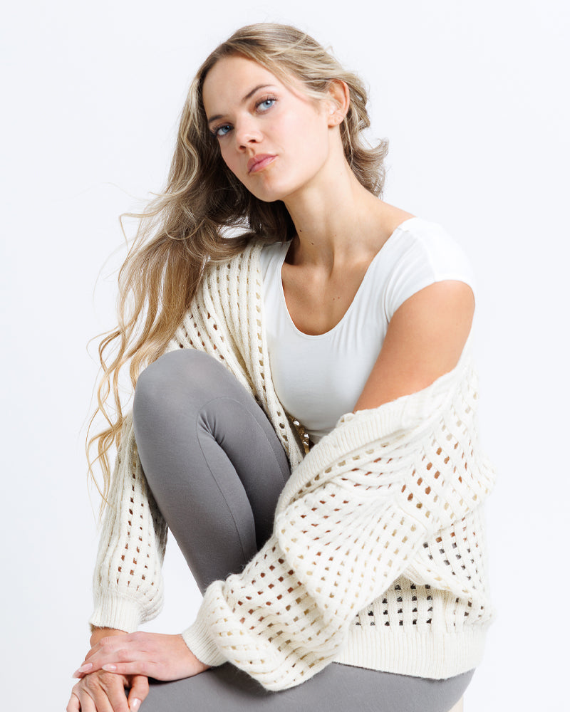 Model wearing an egret colored short sleeve scoop neck cropped tee.