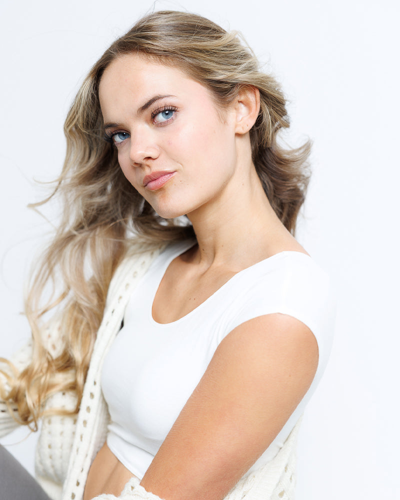 Model wearing an egret colored short sleeve scoop neck cropped tee.