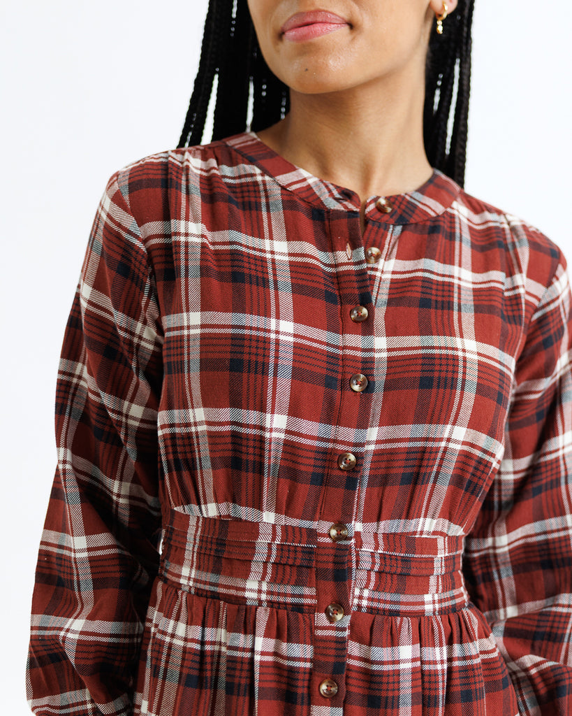 Red and white plaid shirt worn by a person on a plain background