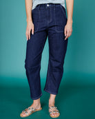 Person wearing dark blue jeans against a teal background