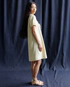 Woman wearing a light-colored dress against a dark blue curtain