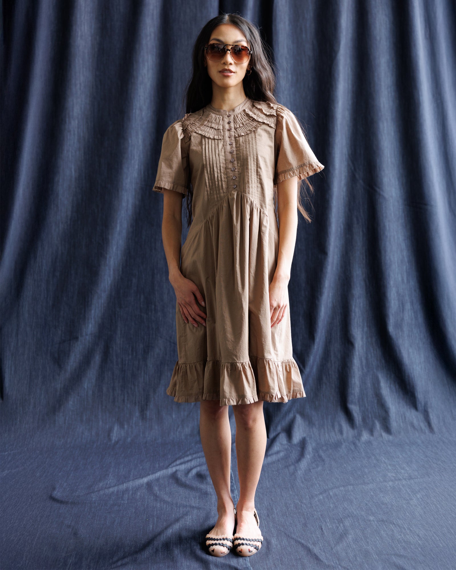 Woman wearing a beige dress against a dark blue backdrop