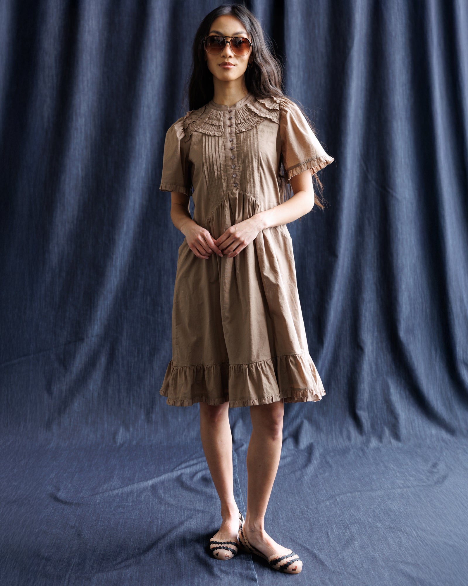 Woman wearing a brown dress against a dark blue backdrop