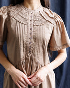 Brown dress with a textured collar against a dark background