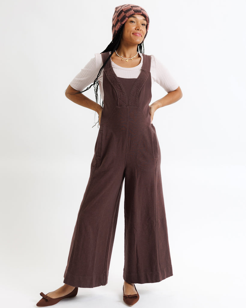Woman wearing brown overalls on a white background