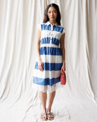 Woman wearing a blue and white striped dress against a plain background