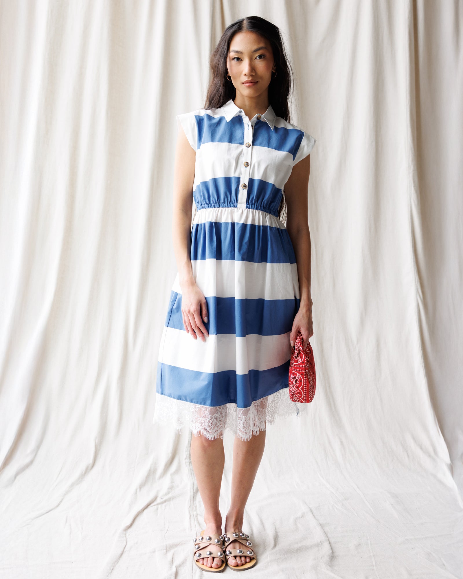 Woman wearing a blue and white striped dress against a plain background