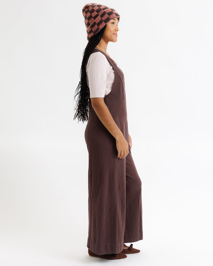 Person wearing a brown dress and checkered beanie on a white background