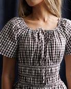 Close-up of a person wearing a brown and white checkered dress with a dark background
