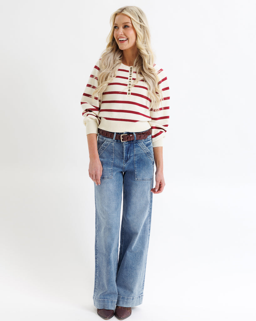 Woman wearing a red and white striped shirt and blue jeans on a white background