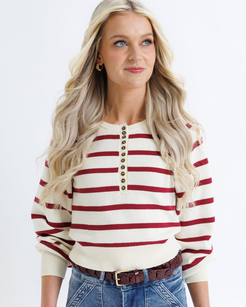 Woman wearing a red and white striped sweater with a plain background