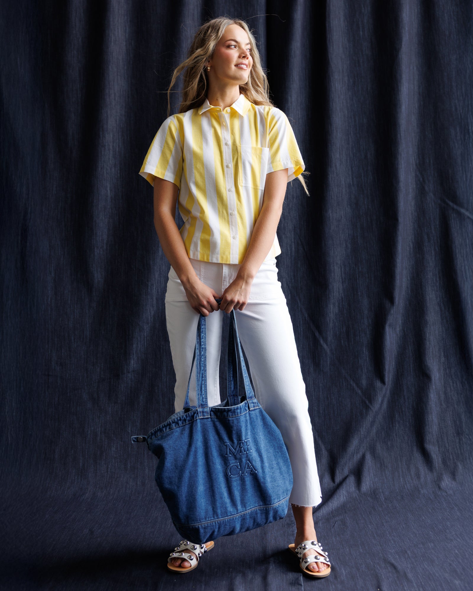 Woman holding a blue denim bag against a black background