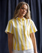 Woman wearing a yellow and white striped shirt against a dark background