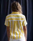 Person wearing a yellow and white striped shirt against a dark background