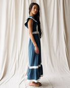 Woman wearing a blue dress with white accents against a plain background