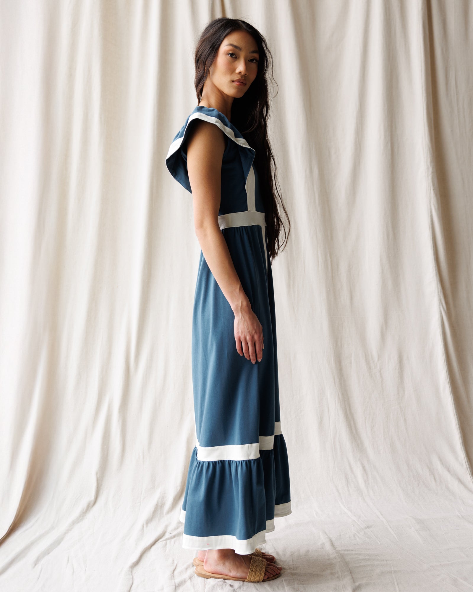 Woman wearing a blue dress with white accents against a plain background