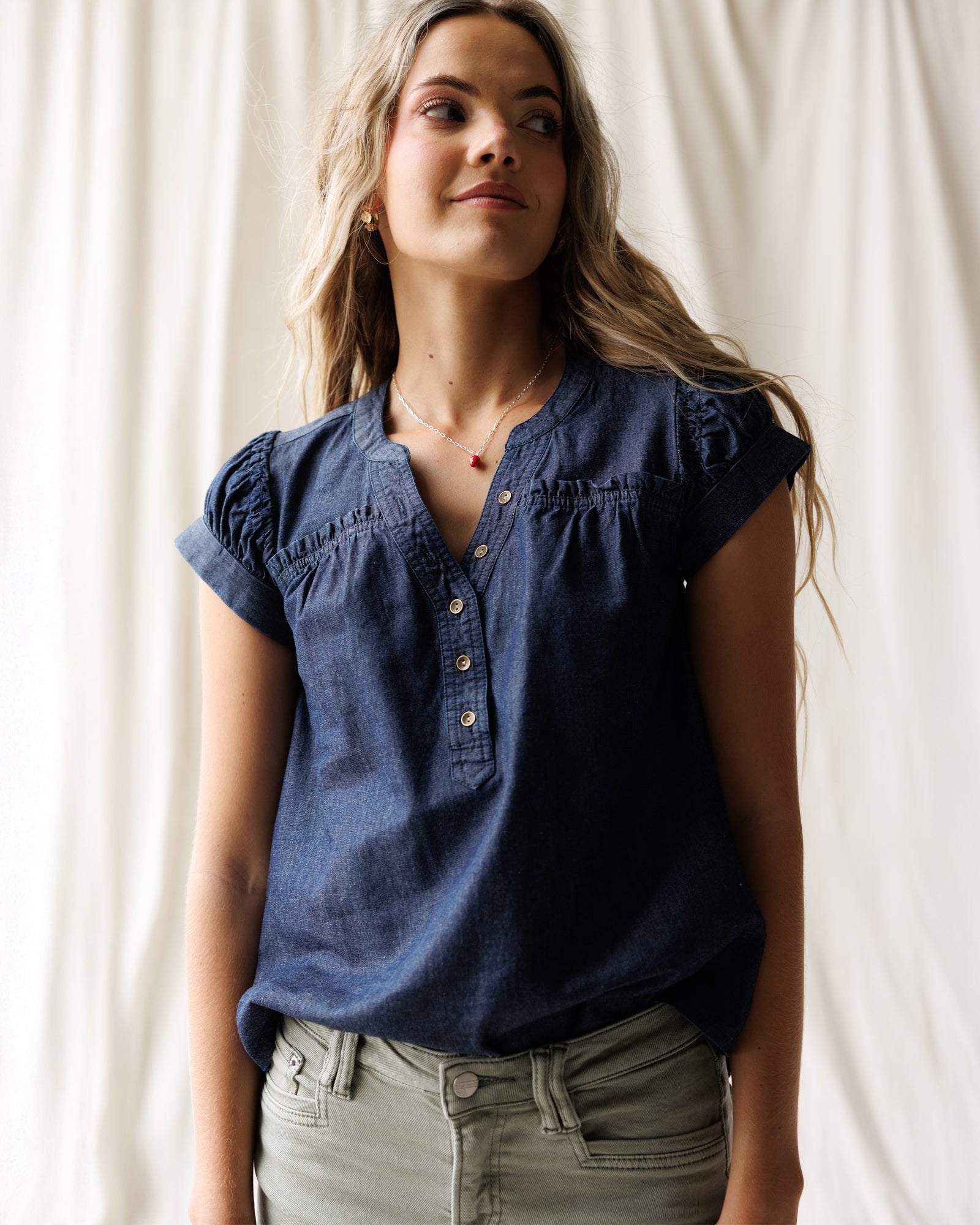 Woman wearing a blue blouse against a white curtain background