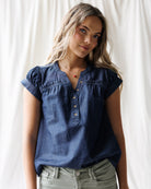 Woman wearing a blue denim top against a white background