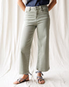 Person wearing light green jeans and a blue top against a white background