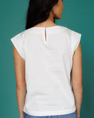 White sleeveless top worn by a person on a teal background