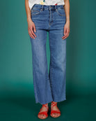 Close up image of person wearing denim jeans against a teal background