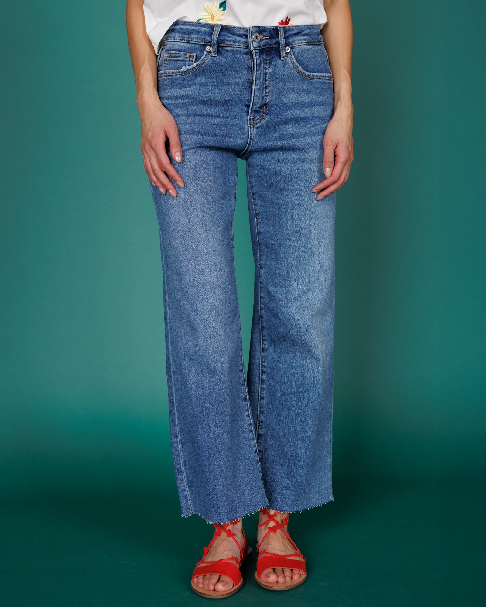 Close up image of person wearing denim jeans against a teal background