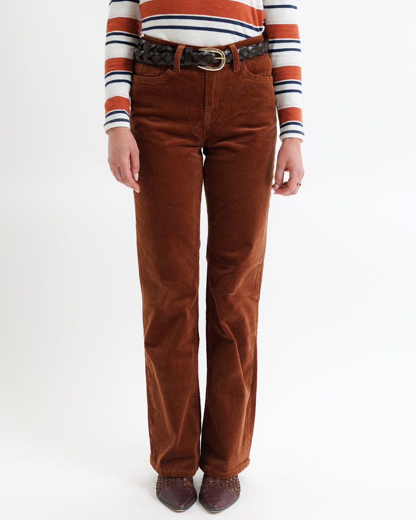 Person wearing brown corduroy pants with a striped sweater on a white background