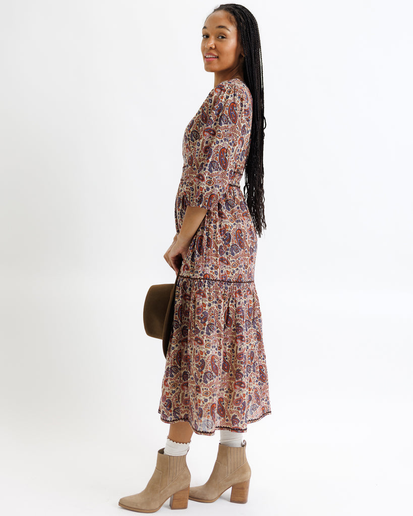 Woman wearing a floral dress with beige boots on a white background
