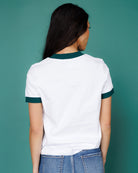 Person wearing a white t-shirt with green trim against a teal background