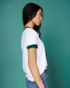 Woman wearing a white t-shirt with green accents against a teal background
