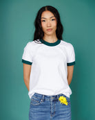 Person wearing a white ringer shirt with green trim against a teal background