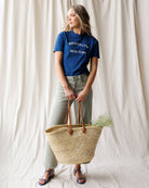 Woman holding a woven basket against a white curtain backdrop