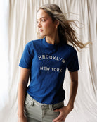 Woman wearing a blue t-shirt with text against a neutral background