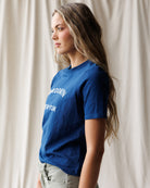 Woman wearing a blue t-shirt with text against a neutral background