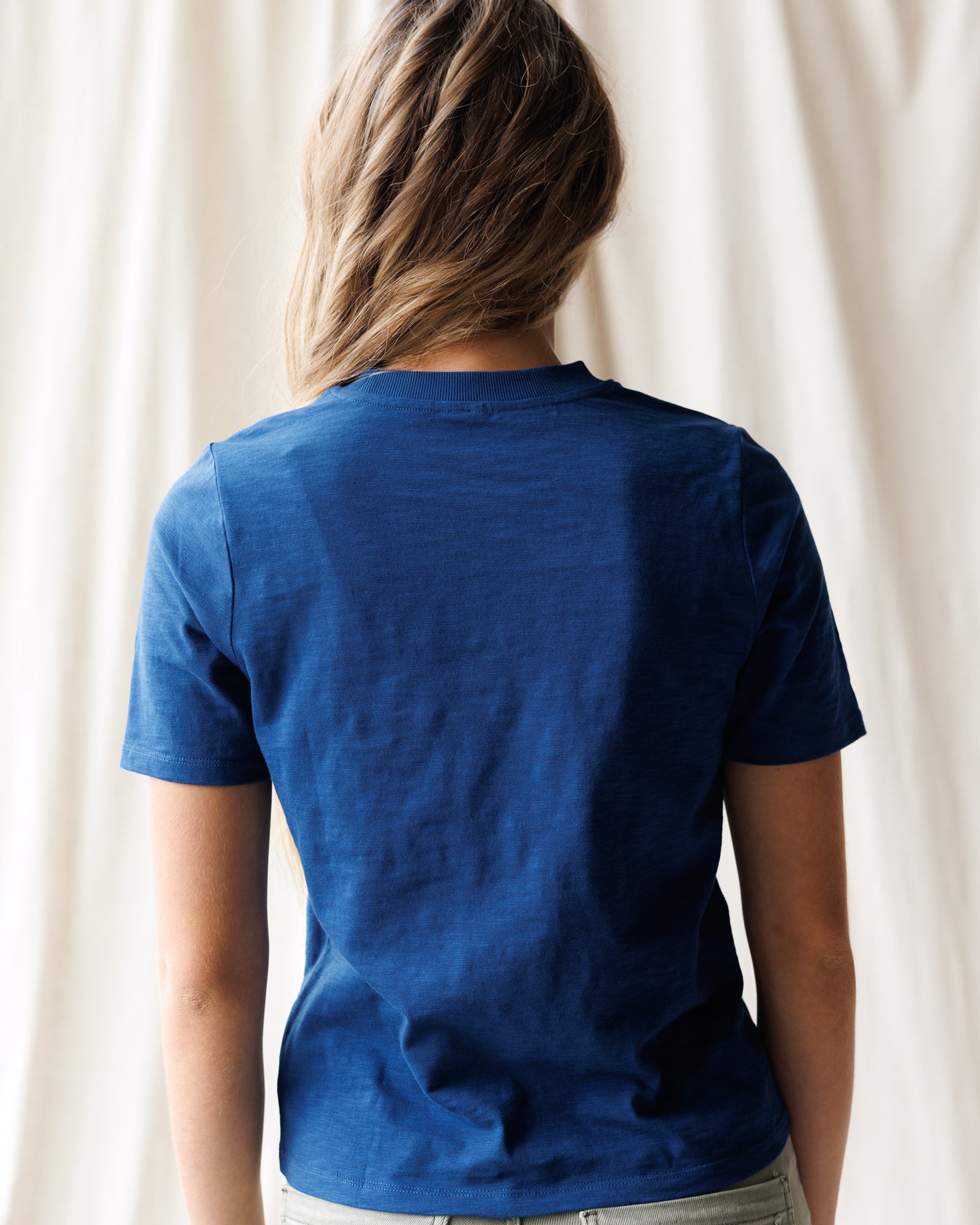 Person wearing a blue t-shirt with a plain background