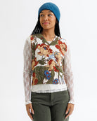 Woman wearing a floral patterned top with lace sleeves on a white background