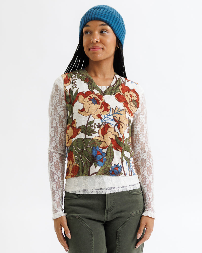 Woman wearing a floral patterned top with lace sleeves on a white background