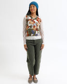 Person wearing a floral sweater and green pants on a white background