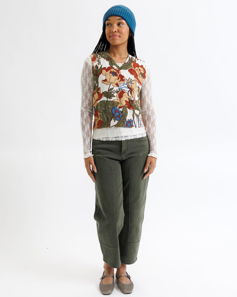 Person wearing a floral sweater and green pants on a white background