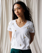 Woman wearing a white t-shirt with floral patterns against a neutral background